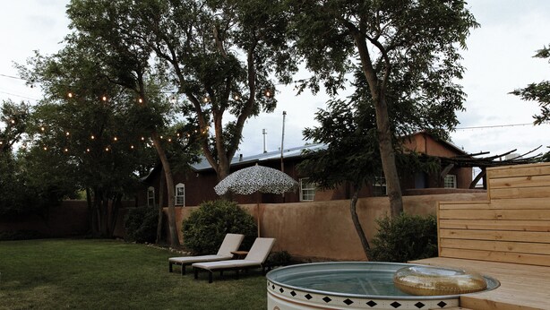 A backyard with a hot tub, two lounge chairs, and string lights. - Hot Tub + Pool! Yucca Suite at The Desert Compass (Albuquerque)