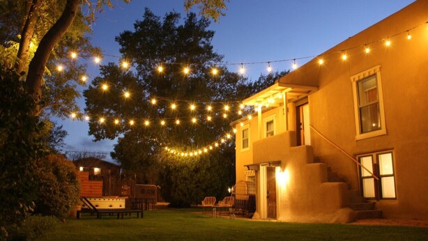 Une maison avec une véranda, une petite terrasse et une guirlande de lumières.