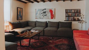 Una sala de estar moderna con un sofá modular, una mesa de centro de madera y una alfombra roja con estampado.