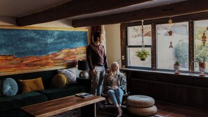 A cozy living room with a green sofa, a wooden coffee table, and a colorful abstract painting on the wall.