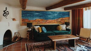 A cozy living room with a large painting of a starry night sky, a green sofa, a wooden coffee table, and a wicker chair.