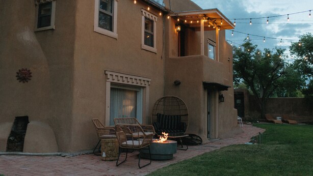 A house with a patio area featuring wicker chairs, a fire pit, and string lights.