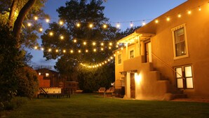 A house with a covered patio, a wooden deck, and a string of lights. - Hot Tub + Pool! Coyote Suite at The Desert Compass in Old Town (Albuquerque)