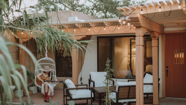 A patio area with outdoor seating, a hanging chair, and string lights. - Hot Tub + Pool! Coyote Suite at The Desert Compass in Old Town (Albuquerque)