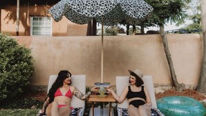 Two lounge chairs with a table between them, a leopard print umbrella, and a green inflatable tube. - Group Gatherings ☀ Property Buyout at The Desert Compass (Albuquerque)