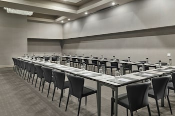 A banquet hall with round tables, white tablecloths, and chairs, arranged for a formal event. at The Satire, Autograph Collection