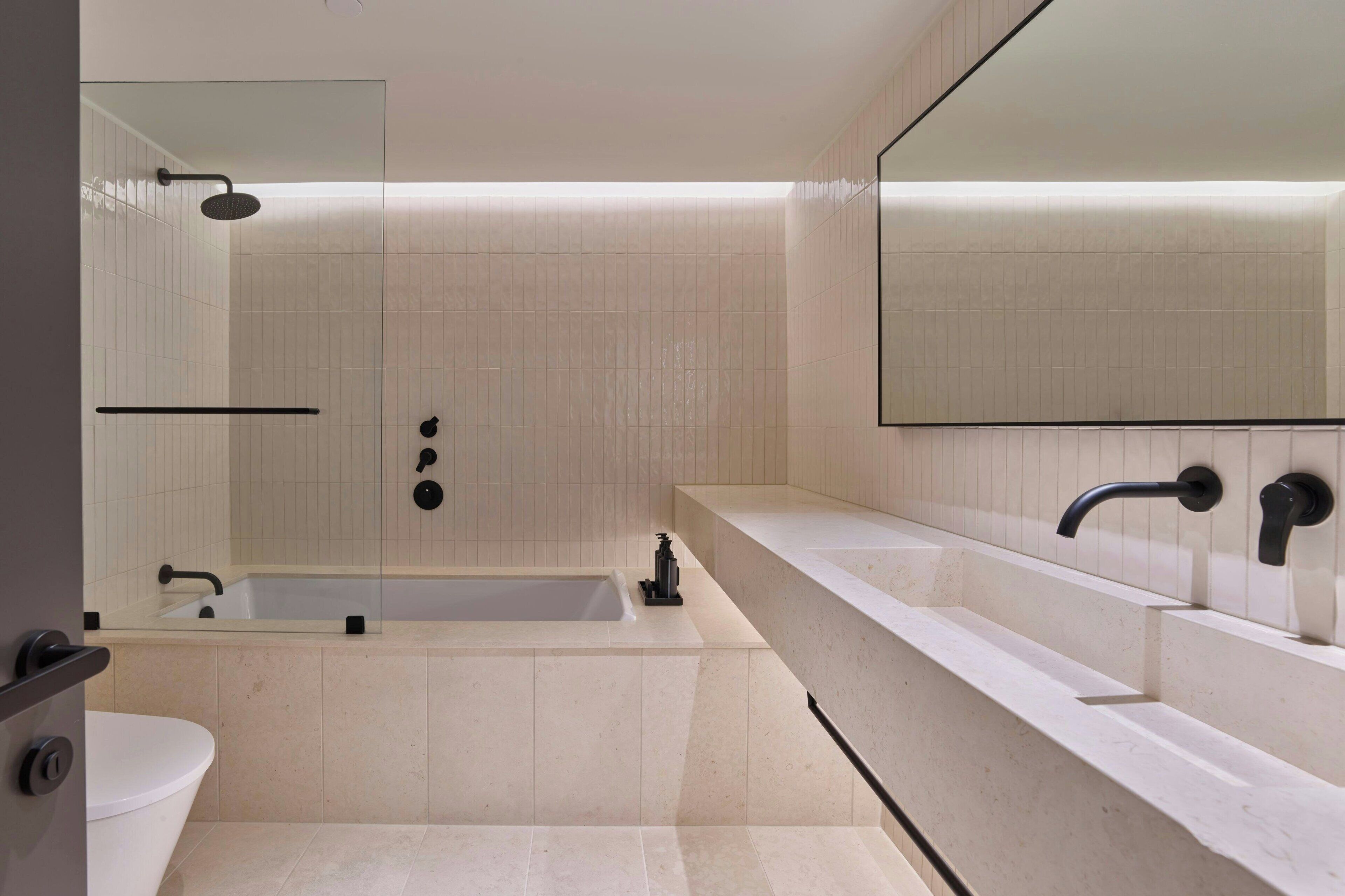 A modern bathroom with a bathtub, a large mirror, and a sink.