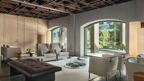 Ein modernes Wohnzimmer mit einem großen Fenster, einem runden Glastisch und zeitgemäßen Möbeln.