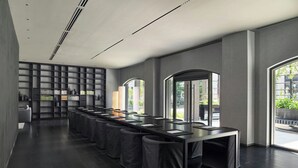 Ein modernes Hotelzimmer mit einem langen Esstisch, dunklem Holzboden und großen Fenstern mit Blick ins Freie.