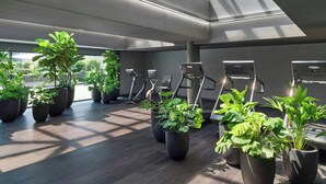 Ein Fitnessraum mit Trainingsgeräten und Topfpflanzen.