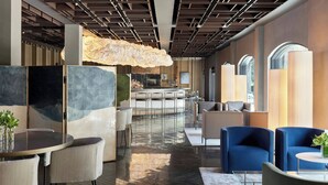 Eine moderne Hotelhalle mit Barbereich, Sitzgelegenheiten und einem außergewöhnlichen Deckenstil.