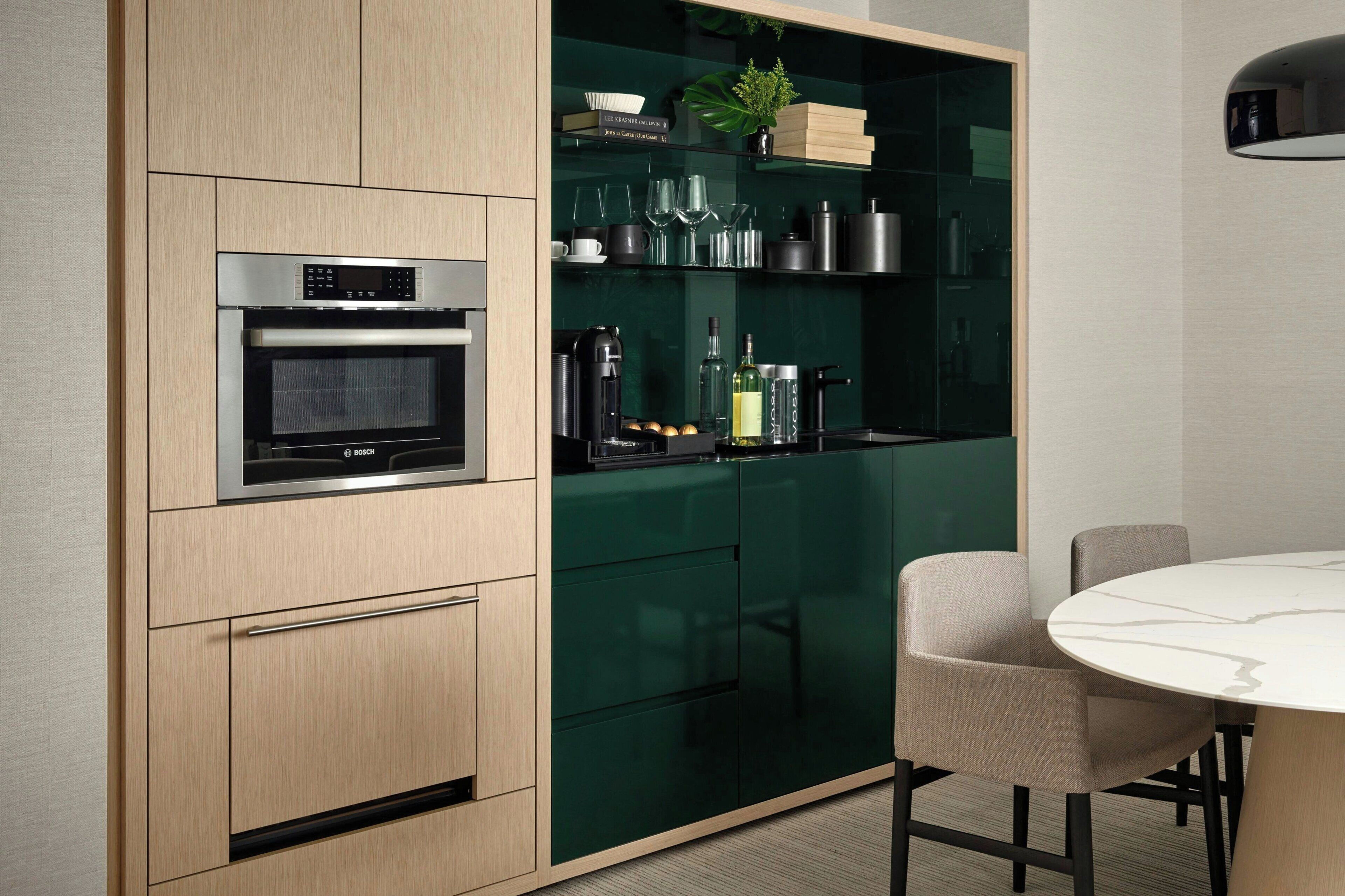 A modern kitchen with a Bosch oven, green cabinets, and a dining table with chairs.