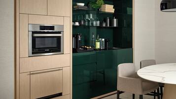 A modern kitchen with a Bosch oven, green cabinets, and a dining table with chairs.