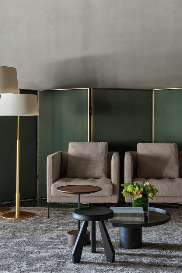 A modern living room with a sofa, a coffee table, a floor lamp, and a vase with flowers.