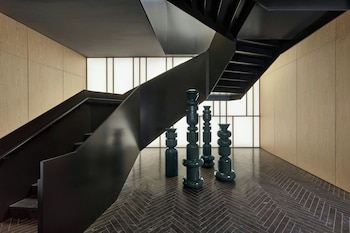 A modern hotel with a brick facade, large windows, and outdoor seating with umbrellas. at The Satire, Autograph Collection