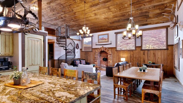 Ein rustikales Interieur mit Holzbalkendecke, Kamin, Essbereich und Treppe.
