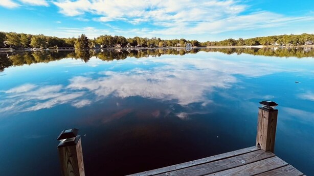 Une jetée en bois s’étendant sur une étendue d’eau calme, sous un ciel dégagé.