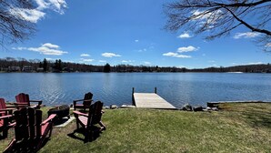 Une vue sur le lac, avec un quai, des chaises Adirondack rouges et une pelouse.