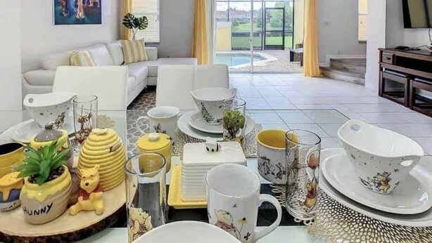 A living room with a sofa, a coffee table, and a dining table set with tea cups and saucers.
