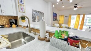 A modern kitchen with a stainless steel sink, a decorative mirror, and a ceiling fan.