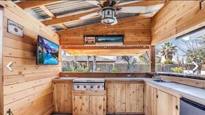 A wooden cabin with a kitchen area, a mounted TV, and a sign for 'Jameson'.