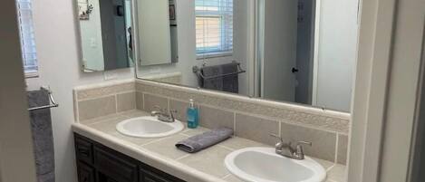 Un baño con dos lavamanos, armarios de madera oscura y un espejo grande.