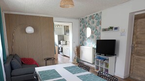 A compact living space with a dining table, sofa, and a television. - Detached house with enclosed garden (Abbeville)