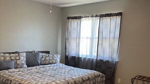 A bedroom with a bed, a ceiling fan, and a window with patterned curtains. - Condo by Kataluma Nighlty Rentals! (Iowa Park)