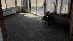 A covered patio area with a seating area, a heater, and a view of the backyard through large windows. - Condo by Kataluma Nighlty Rentals! (Iowa Park)