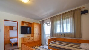 Une chambre à coucher avec deux lits en bois, une armoire en bois, un téléviseur et une fenêtre avec des rideaux.