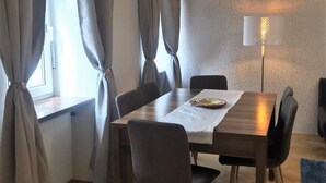 A dining area with a wooden table, four chairs, and a lamp. - Wohnung in Hernals (Wien)