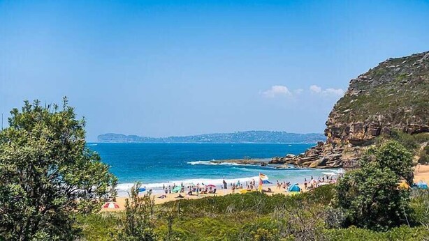 A beach with rocky cliffs, clear blue sea, and people enjoying the beach. - Stunning Beach Views With Pool. Easy Walk To Beach (KILLCARE)