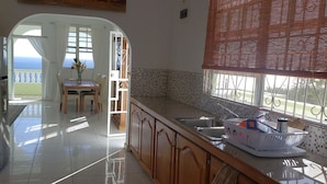A kitchen with a view of the sea, a dining area, and a sink with a boat-shaped soap dispenser. - 5 Mins from beach! (Mero)