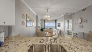 Una cocina moderna con encimera de granito, pileta de acero inoxidable y una lámpara de araña.