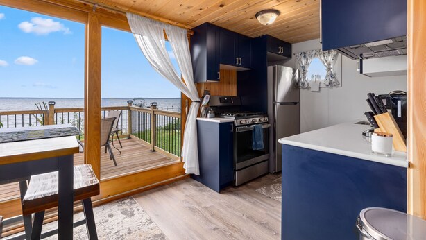 A compact kitchen with a view of the sea, a wooden deck, and a dining area. - Cozy cabin steps from the lake! (Brainerd)