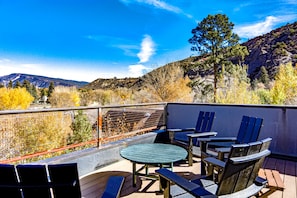 Eine Terrasse mit Sitzgelegenheiten und Blick auf eine gebirgige Landschaft, bewölkter Himmel.