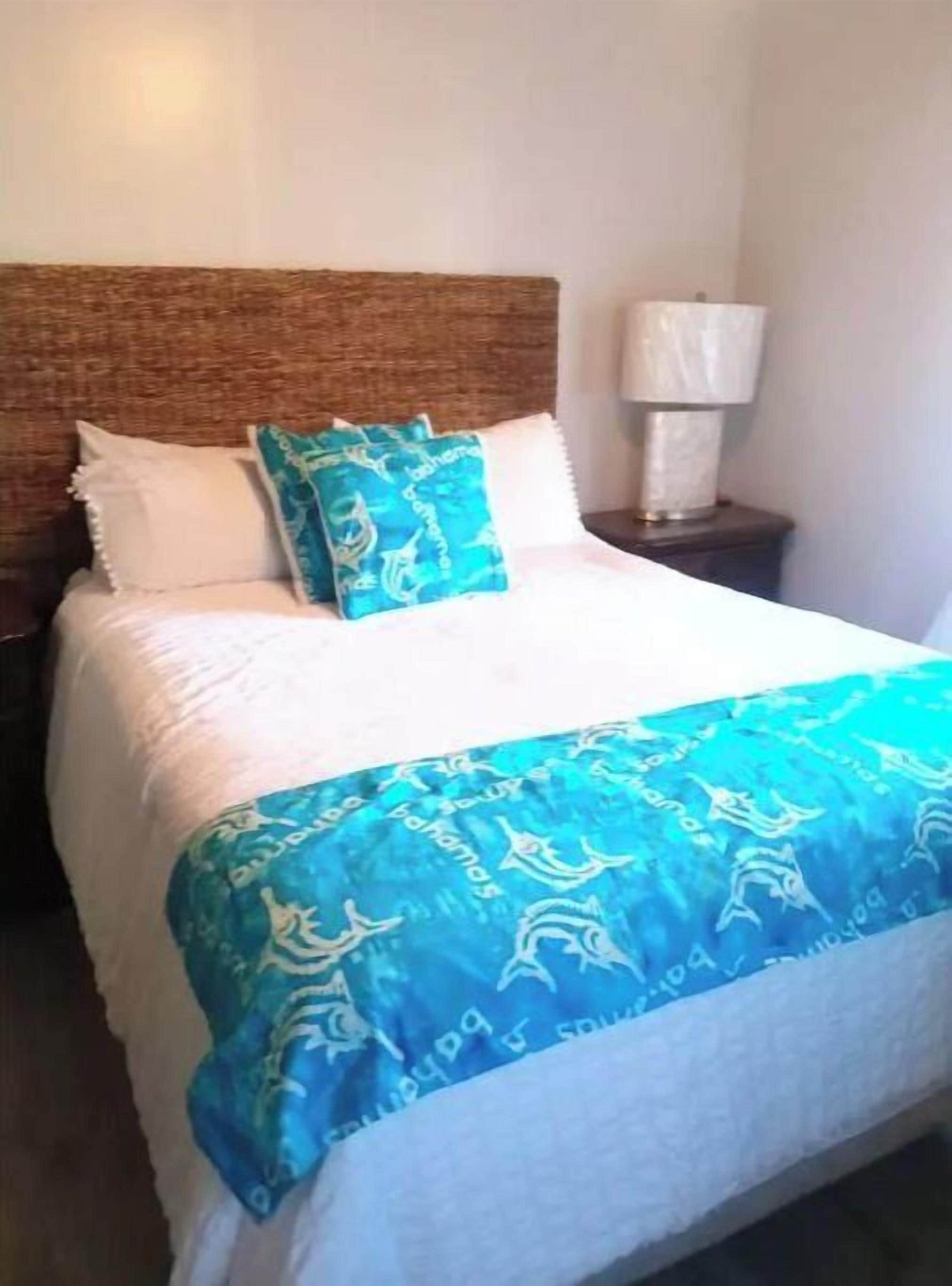 A bed with a white headboard, a blue and white patterned blanket, and a matching pillow.