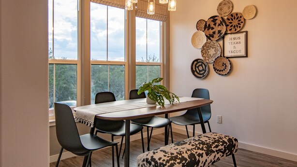 A dining area with a table, chairs, a bench, a chandelier, and a wall with decorative plates and a framed sign. - Hill Country Guest Retreat Near Wedding Venues, Breweries, & Wineries (Dripping Springs)