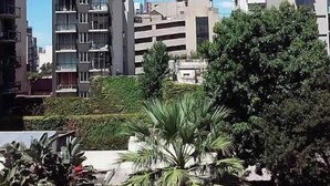 Un moderno edificio de apartamentos con varios pisos, balcones y cielo despejado.