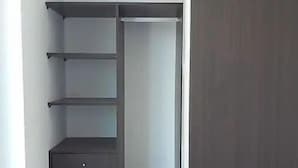 Un armario con repisas abiertas, una barra para colgar ropa y un pequeño conjunto de cajones.