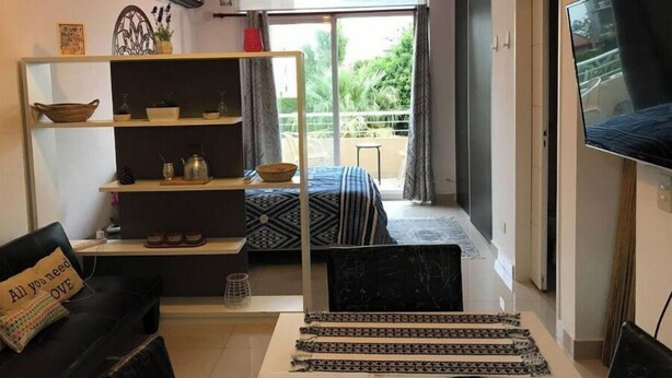 Una sala de estar moderna con un sofá, una mesa de centro, un televisor, una estantería y un balcón con vistas.