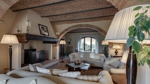 Una sala de estar amplia con techo de ladrillo, chimenea y un gran ventanal de arco.