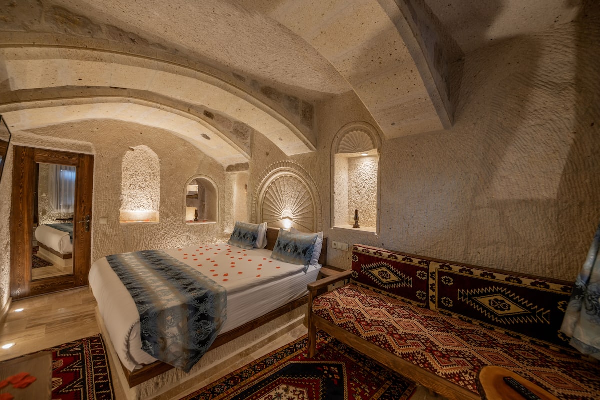 A bedroom with a large bed, a wooden bench, and a patterned rug.