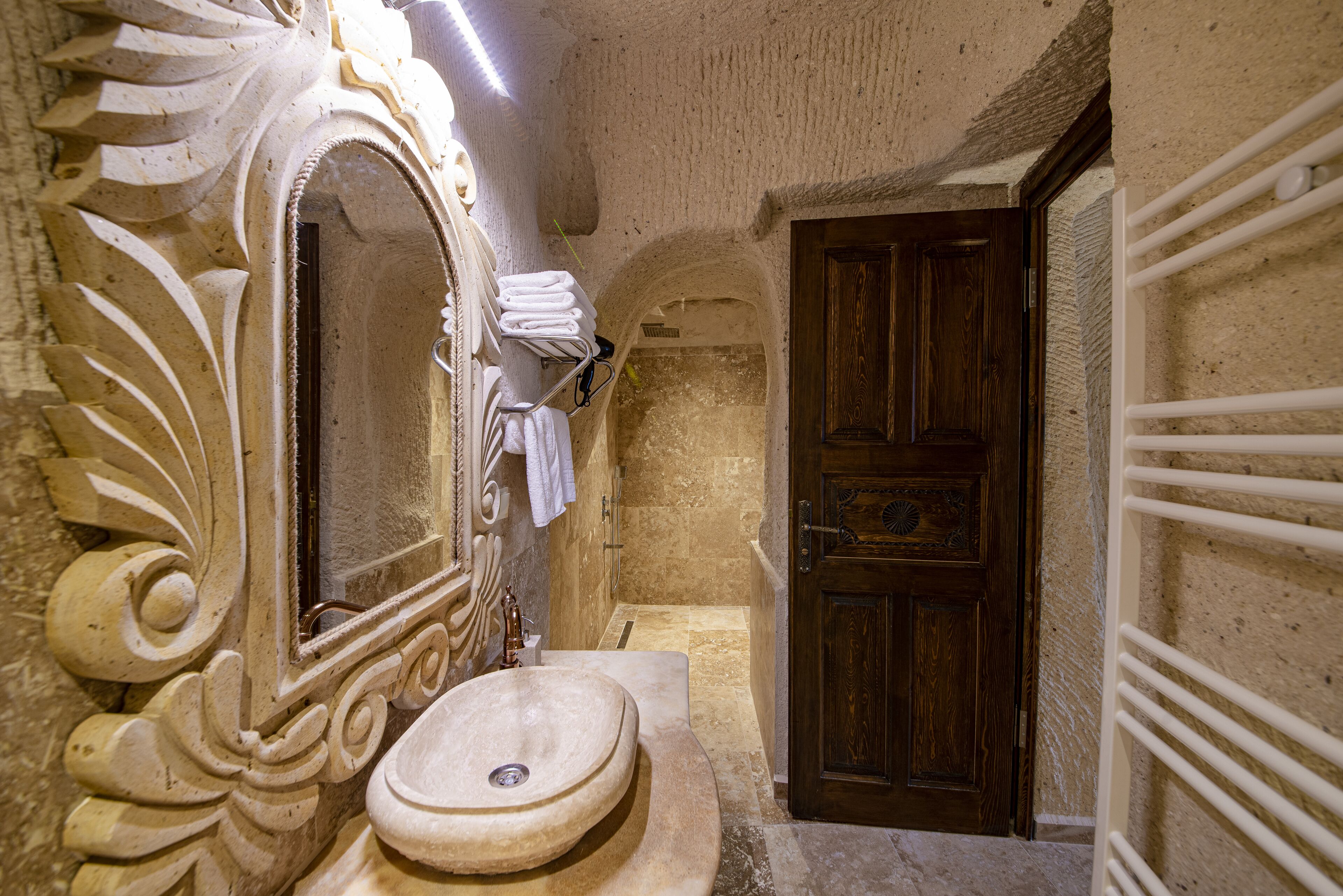 A bathroom with a large ornate mirror, a sink, and a wooden door.