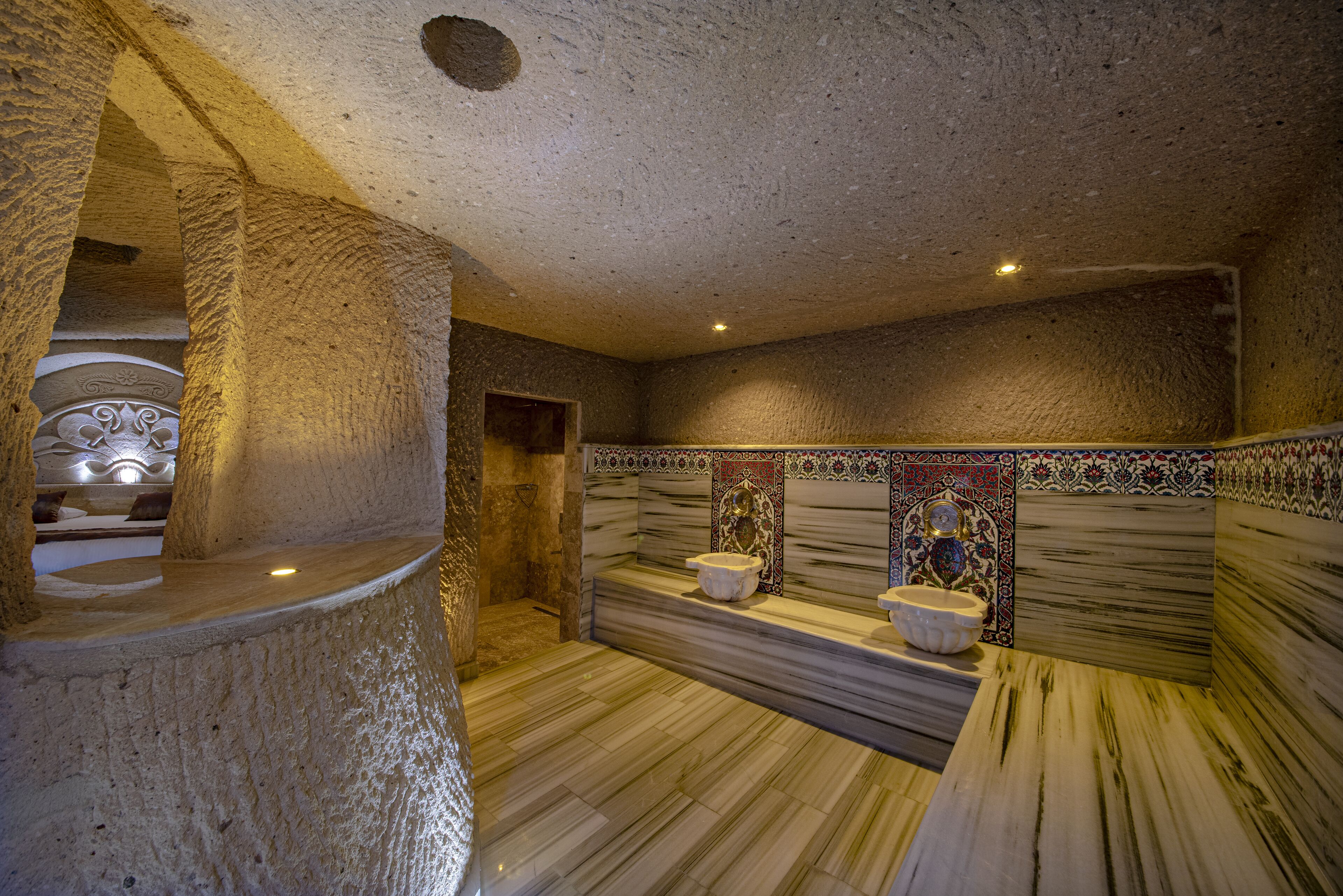 A stone-walled bathroom with marble flooring, a sink, and a toilet.