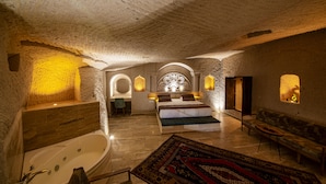A luxurious bedroom with a large bed, a bathtub, and a sofa. - Farmer Cave House (Ürgüp)