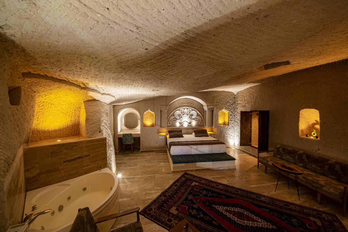 A luxurious bedroom with a large bed, a bathtub, and a sofa.