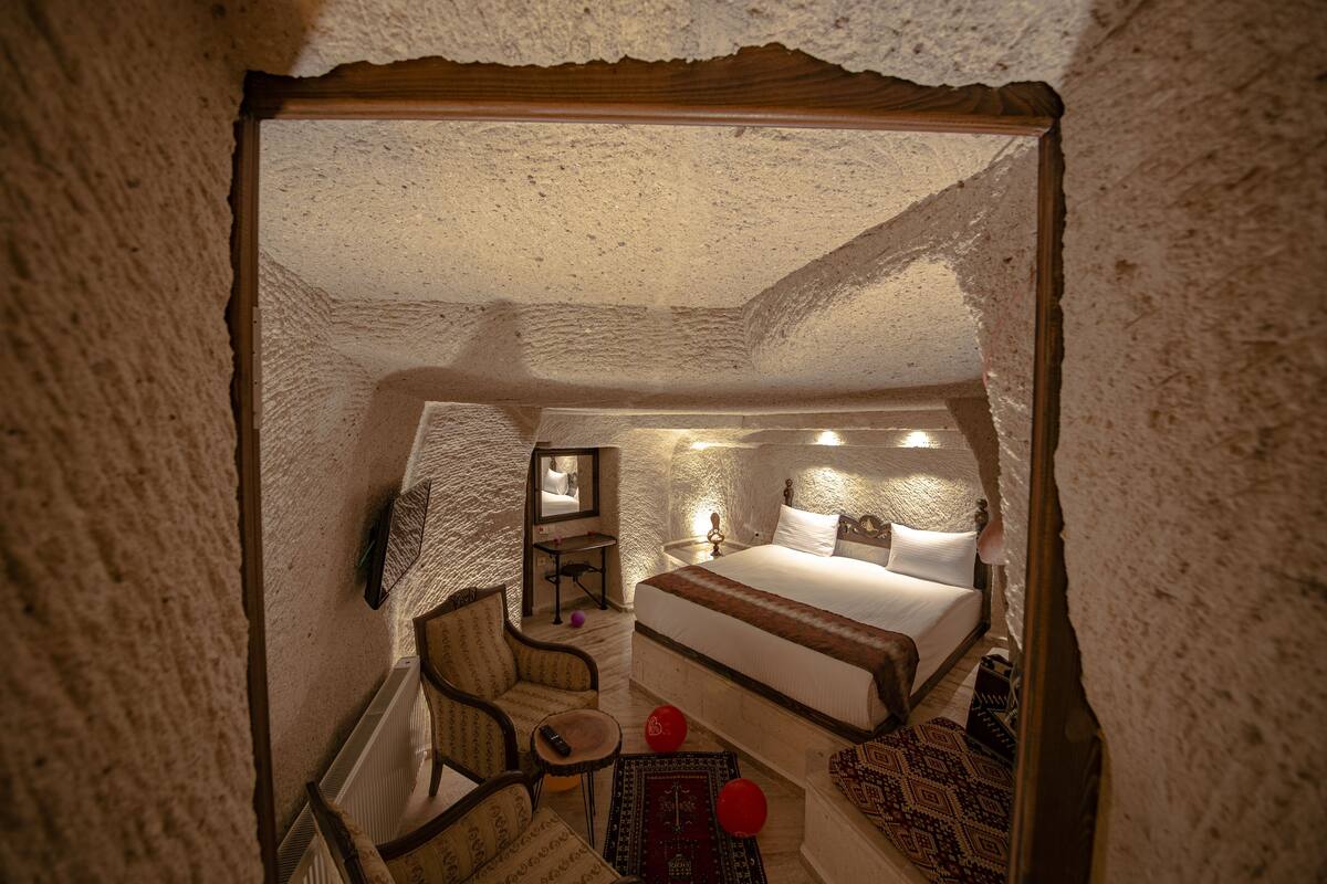 A cozy, rustic bedroom with a large bed, a small seating area, and a mirror.