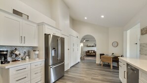 Une cuisine moderne avec des meubles blancs, des appareils en acier inoxydable et un coin repas en bois.