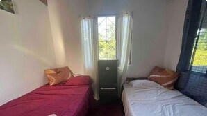 A room with two beds, a window with curtains, a door, and a radiator. - House with excellent location in Bagaces Guanacaste (Salitral)
